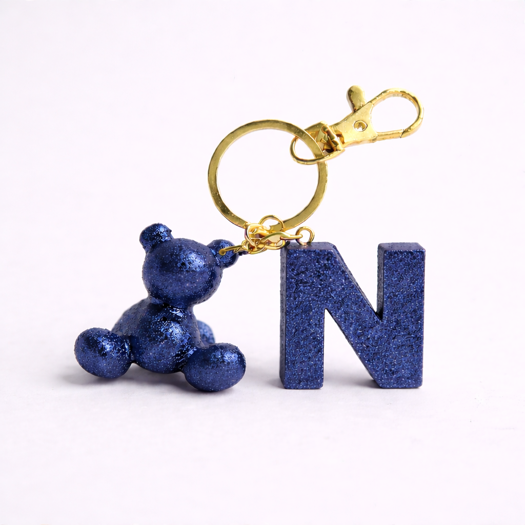 Blue handmade resin bear keychain with the letter N on a bag
