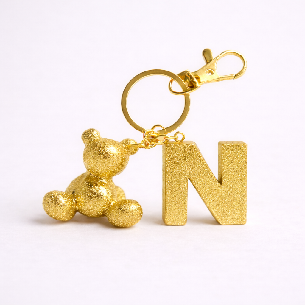 Gold handmade resin bear keychain with the letter N on a bag